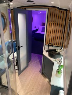 a bathroom with a sink, mirror and shower in it's center area is lit up by purple light