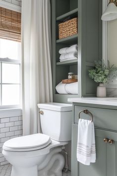 a white toilet sitting in a bathroom next to a window with curtains and towels on it