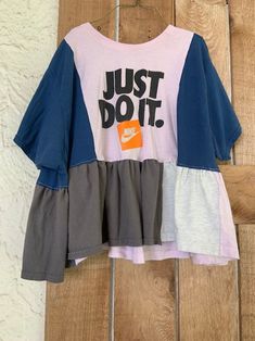 a t - shirt with the words just do it on it hanging up against a wooden wall