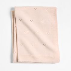 a white blanket with holes on it and a light pink scarf hanging from the side