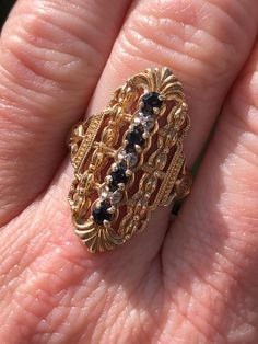 10K yellow gold vintage shield ring. This stunner of a ring has natural sapphires and diamonds running vertically down the center. The sapphires are a deep blue, almost black, and the diamonds are tiny single cuts. The mounting is the star of this show! It's so intricate! It has bead work, filigree, Nuevo nods and ribbons. A must see in person! I'm dating this ring 1950's but I'm betting it's even older. It's LONG, measuring 28.0mm but still so comfortable to wear. Finger size is 6.25 Resizing, if needed, comes complimentary. Feel free to message me if you have any other questions. Shield Ring, Fantasy Jewelry, Natural Sapphire, The Star, Rings Statement, Deep Blue, Bead Work, Halloween Shopping, Statement Rings