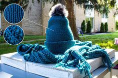 a blue knitted hat and scarf sitting on top of a wooden box in front of a house