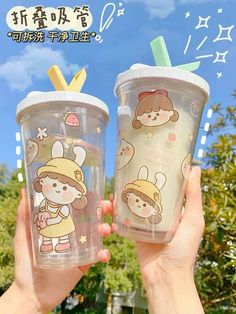 two people holding up plastic cups with straws in their hands and cartoon characters on them