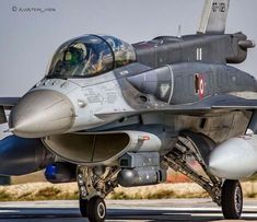 a fighter jet sitting on top of an airport tarmac with its pilot looking out the window