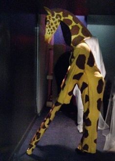 a man in a giraffe costume standing next to a chair