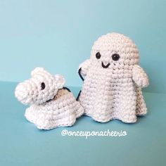 two small crocheted stuffed animals sitting next to each other on a blue surface