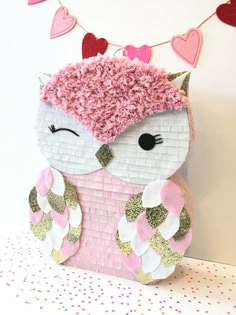 a stuffed animal with pink and white fur sitting on top of a table next to a wall