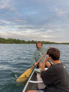 a man and woman in a canoe on the water with their oars facing each other