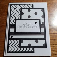 a happy birthday card with black and white designs on the front, sitting on a wooden table