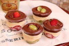 four desserts with chocolate frosting and fruit on top