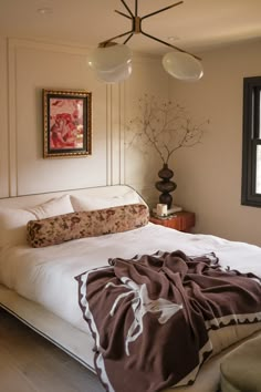 a bedroom with a large bed covered in blankets and pillows, next to a painting on the wall