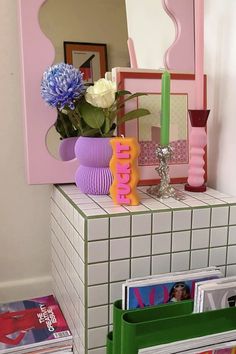 a vase filled with flowers sitting on top of a table next to a mirror and magazines