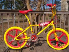 a yellow and red bike sitting on top of a wooden deck