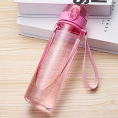 a pink water bottle sitting on top of a table next to a stack of books