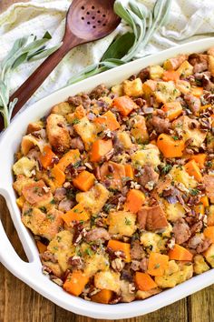 a casserole dish filled with stuffing and vegetables on top of a wooden table