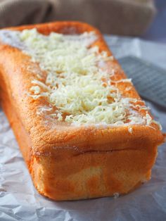 a loaf of bread covered in cheese on top of wax paper