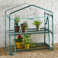 a green house filled with potted plants next to a white brick wall and floor