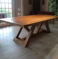 a large wooden table sitting on top of a hard wood floor next to a window