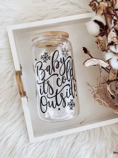 a baby it's cold outside mason jar next to cotton flowers