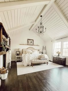 a bedroom with white walls and wood flooring has a chandelier hanging from the ceiling