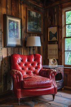 a red leather chair sitting in a living room next to a lamp and pictures on the wall