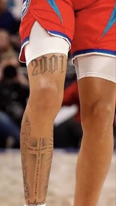 the legs and ankles of a basketball player with tattoos on his leg, while wearing red shorts