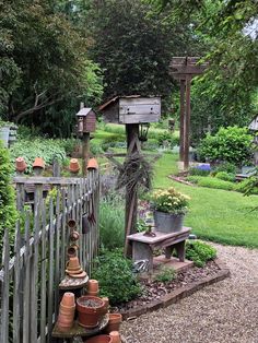 a garden with lots of potted plants on the ground next to a wooden fence