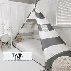 a child's teepee tent bed with grey and white stripes on it, next to a small table