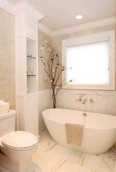 a white bathtub sitting next to a toilet under a window in a bathroom with marble flooring