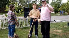 three people standing in the grass holding baseball bats