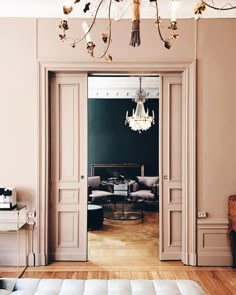 an open door leading to a living room with chandelier