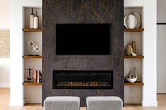 a living room with two chairs and a television mounted on the wall above it's fireplace