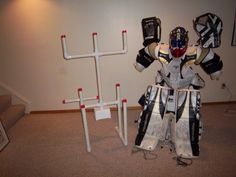 a robot made out of hockey goalies is standing in front of a wall with three poles