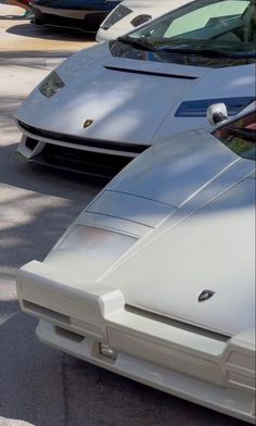 the front end of a white sports car parked next to other cars in a parking lot