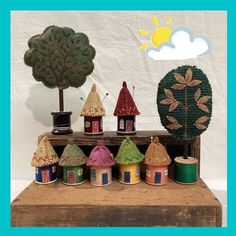 a group of small houses sitting on top of a wooden box next to a tree