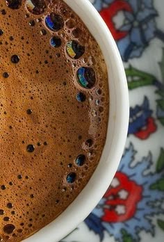 a close up of a cup of coffee on a floral table cloth with water droplets