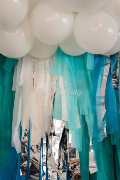 blue and white streamers are hanging from the ceiling in front of an arch with balloons