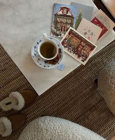 there is a cup of tea on the floor next to some cards and a pair of slippers