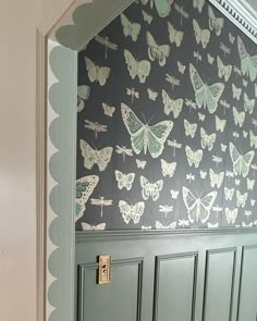 a green door with butterflies painted on the side and scalloped trim around it