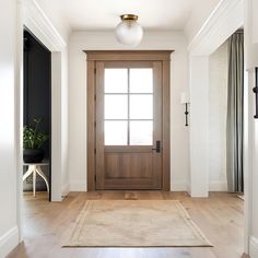 an empty entryway with a wooden door and rug on the floor