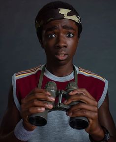 a young man holding two binoculars in his hands and looking at the camera with an amazed look on his face