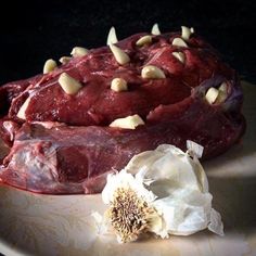 a large piece of meat sitting on top of a white plate next to a flower