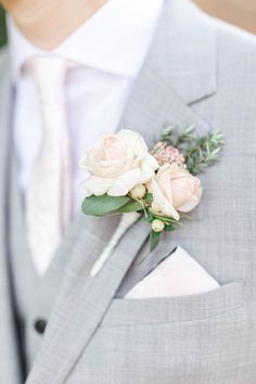 a man wearing a gray suit and white flowers in his lapel flower clip,