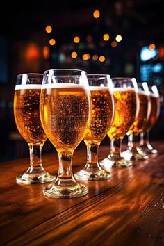 five glasses of beer are lined up on a table