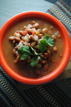 a bowl filled with beans and cilantro on top of a table