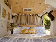 a bed in the back of a camper with lights hanging from it's ceiling