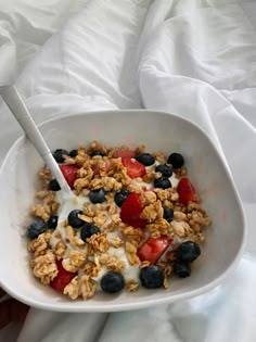 a bowl of granola with yogurt, strawberries and blueberries in it