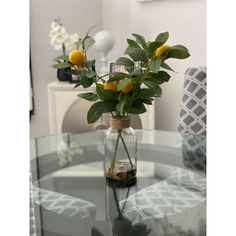 a glass table topped with a vase filled with yellow flowers and greenery sitting on top of it