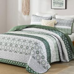 a green and white quilted bedspread in a bedroom