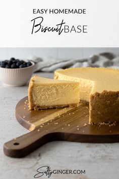 a cheesecake is cut into slices on a wooden cutting board with a bowl of blueberries in the background